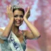 Mladá žena s korunkou královny krásy pláče a usmívá se zároveň