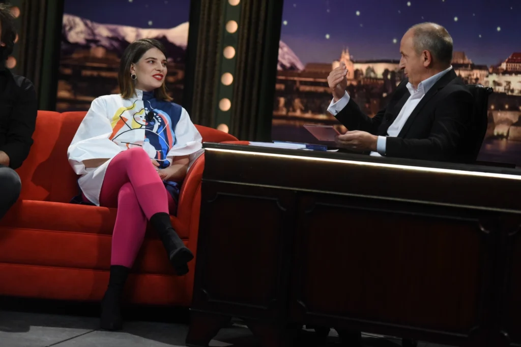 profimedia-0361965986 - VIPshow Žena sedí na červené sedačce, za stolem sedí muž, vede s ní rozhovor