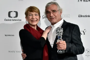 Muž a žena se dívají do objektivu a drží při tom sošku.