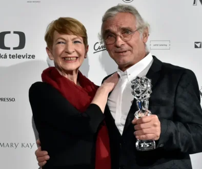 Muž a žena se dívají do objektivu a drží při tom sošku.