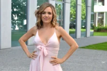 Mladá žena s dlouhými vlasy v romantických růžových šatech pózuje před fotografem