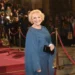žena v modrých šatech se usmívá a pózuje na červeném koberci