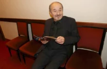 Muž sedí na vínové židli a listuje si časopisem