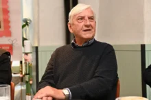 Herec v tmavém svetru sedí a dívá se do strany