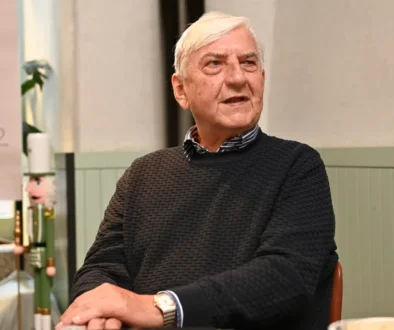 Herec v tmavém svetru sedí a dívá se do strany