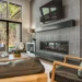 Modern living room with a built-in horizontal fireplace and textured gray tile wall, facing large glass doors to an outdoor seating area.