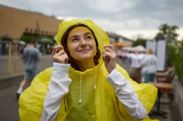 Žena ve žluté pláštěnce se usmívá a dívá se směrem k nebi