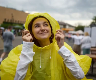 Žena ve žluté pláštěnce se usmívá a dívá se směrem k nebi