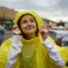 Žena ve žluté pláštěnce se usmívá a dívá se směrem k nebi