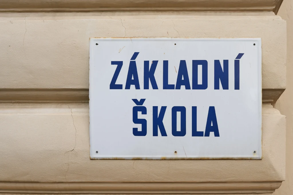 shutterstock_2455257215 - VIPshow Bílá cedule na fasádě s modrým nápisem Základní škola