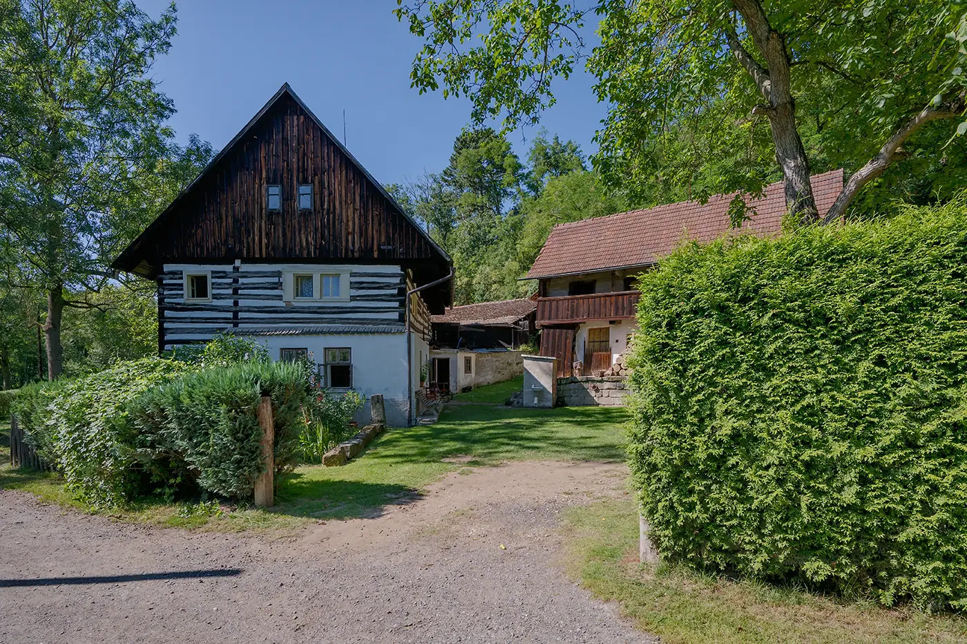 Starý mlýn obklopený zelení za slunečného dne