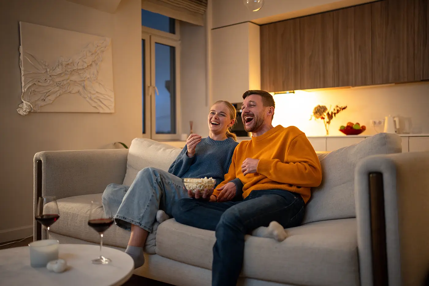 Muž a žena sedí na gauči a dívají se na televizi.