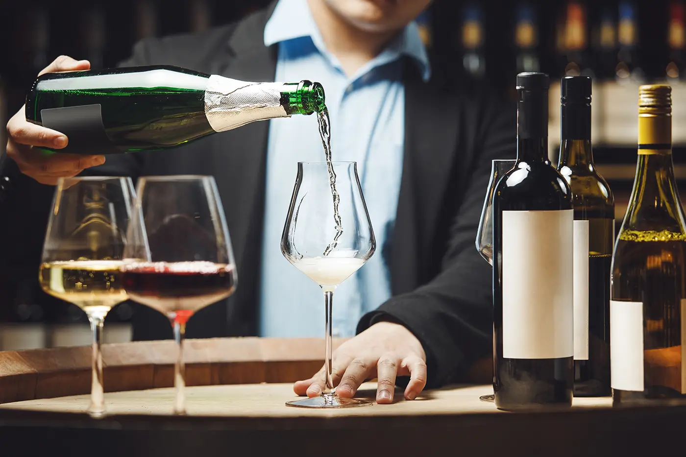 Barman rozlévá bílé víno do sklenic.