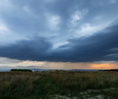 Bouřkové mraky, přes které prosvítá slunce, se kumulují nad krajinou