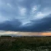 Bouřkové mraky, přes které prosvítá slunce, se kumulují nad krajinou