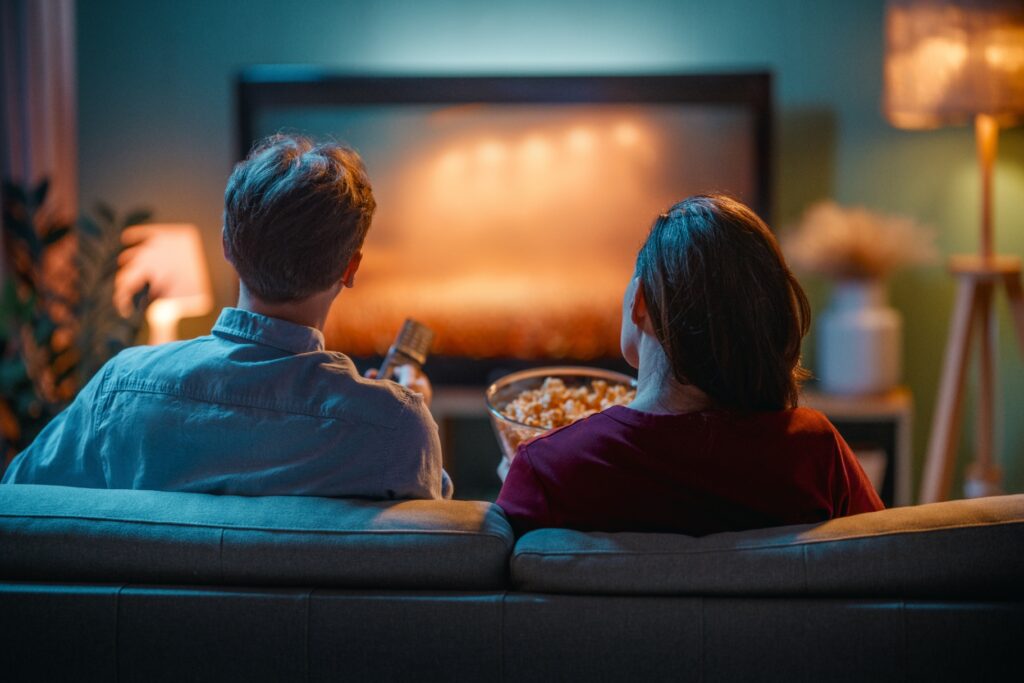 Muž a žena sledují televizi, mají popcorn