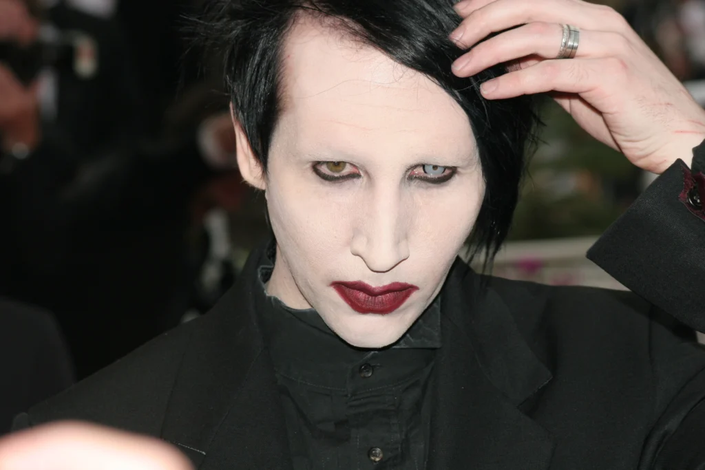 Tvář člověka v drsné masce, bílý makeup, červená rtěnka, uhlově černé vlasy