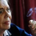 Stará žena v modrém saku a bílé košili kouří cigaretu