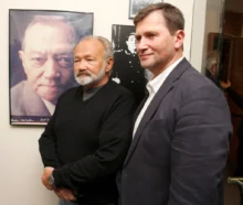 Dva muži v oblecích stojí u fotografie dalšího muže, synové a otec