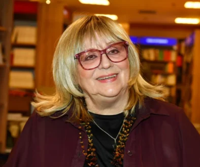 Usmívající se žena ve velkých brýlích a červeném saku