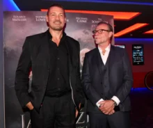 Muži v černých oblecích stojí v kině před plakátem k filmu