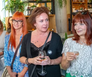 Dvě ženy v popředí si povídají a další dvě ženy stojí opodál