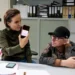 Žena sedí za stolem v pracovně a muž klečí vedle ní