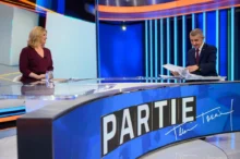Žena a muž naproti sobě sedí ve studiu a debatují