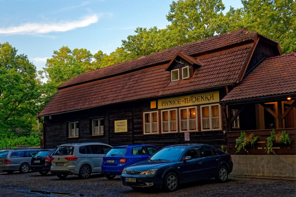 Dřevěná stavba, na ni nápis hájenka, před ní parkuje řada automobilů