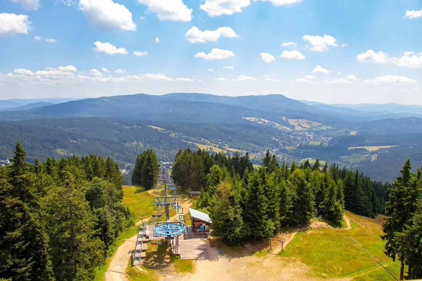 Panoramatický pohled na horskou krajinu plnou lesů, polí a luk