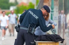 Muž v policejním oblečení kontroluje ženě tašku