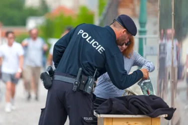 Muž v policejním oblečení kontroluje ženě tašku