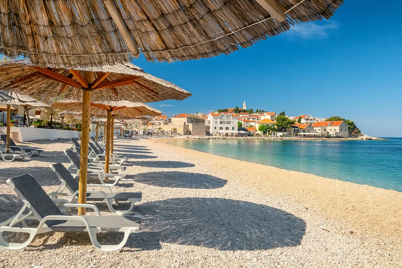 shutterstock_2464824925 - VIPshow Písčitá pláž s lehátky a slunečníky za slunečného dne