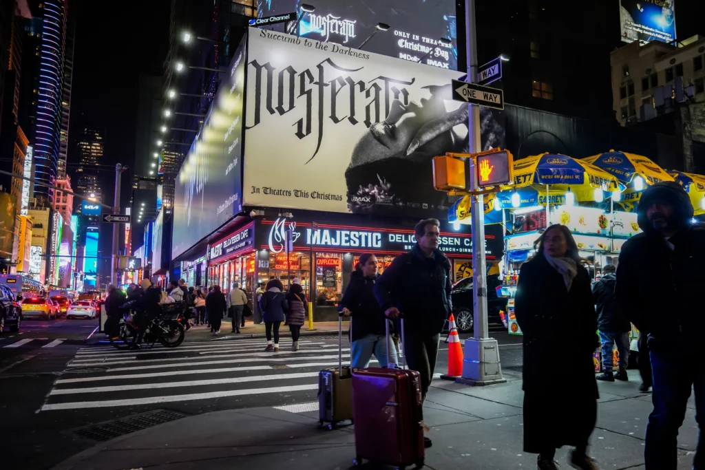 shutterstock_2554742993 - VIPshow Návštěvníci Times Square procházejí v noci pod reklamou na film Nosferatu