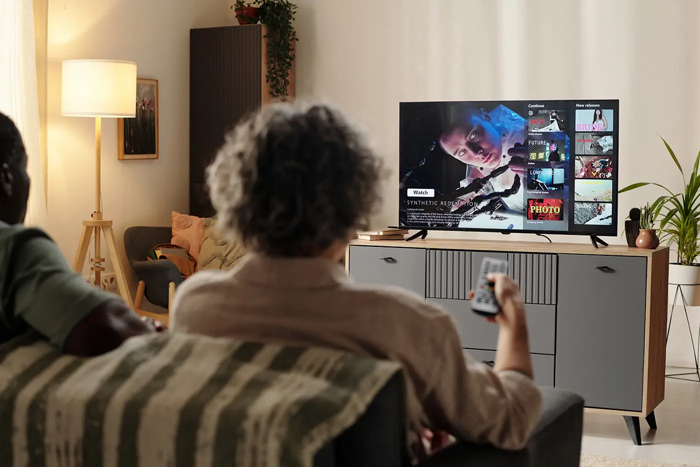 Dva lidé sedí na gauči a dívají se na televizi
