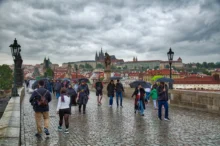 Lidé s deštníky chodí po nejslavnějším pražském mostě