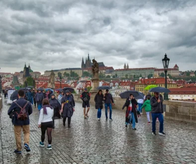 Lidé s deštníky chodí po nejslavnějším pražském mostě