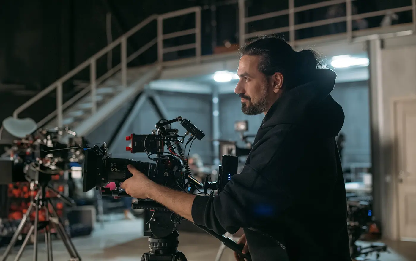 Muž stojí za kamerou ve studiu a míří s ní na scénu