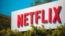 Logo Netflixu na billboardu obklopeného zelenými keři