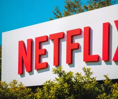 Logo Netflixu na billboardu obklopeného zelenými keři