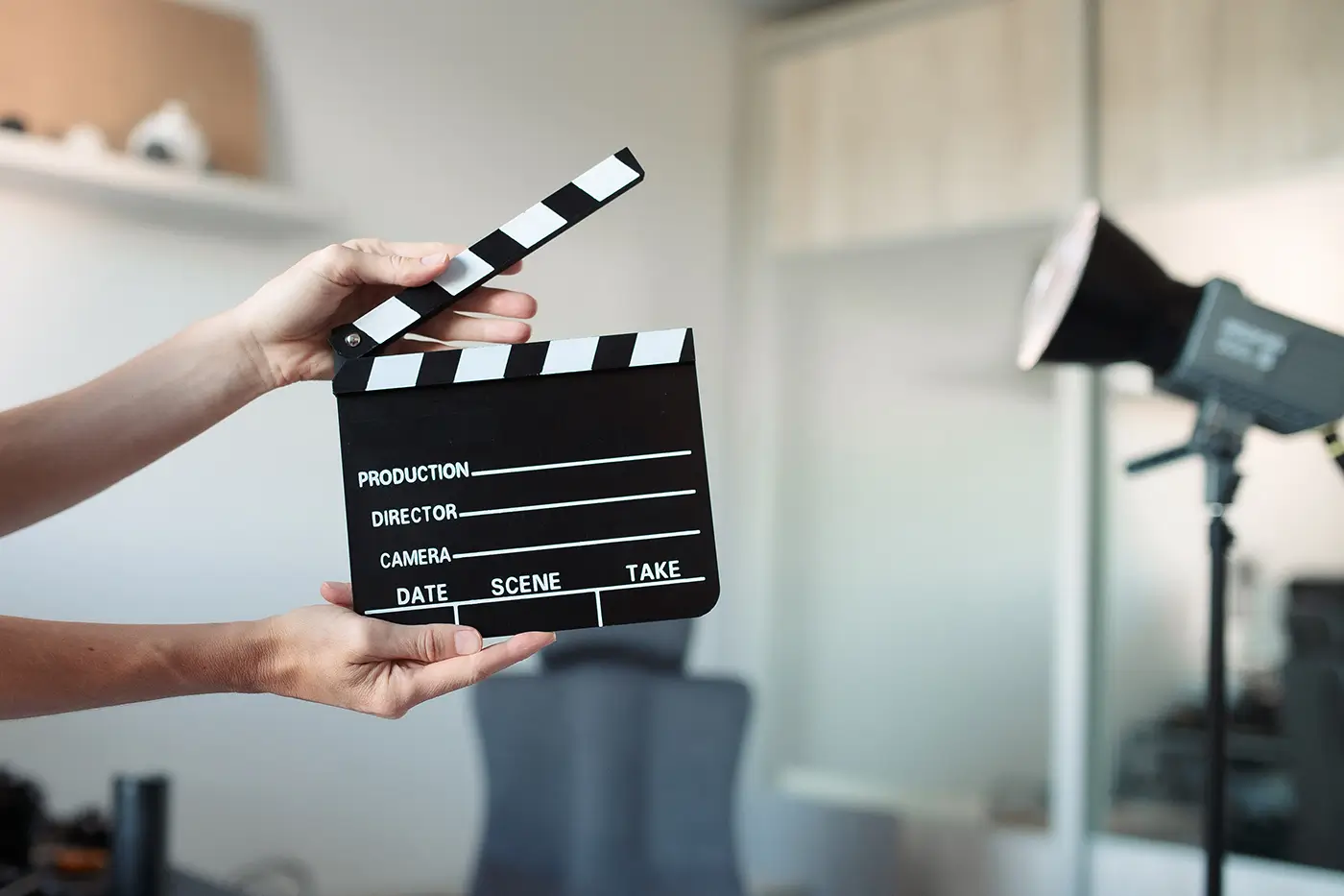 shutterstock_2719909359 - VIPshow Ruce drží filmovou klapku a v pozadí je reflektor
