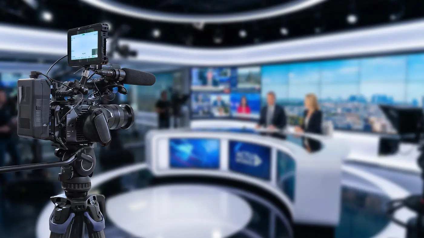Záběr na televizní studio a snímající kamery, které míří na moderátory