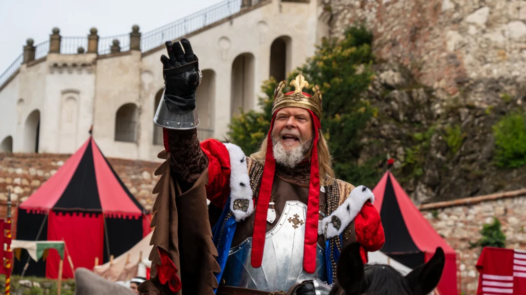 Muž v historickém kostýmu krále na náměstí u starobylé stavby