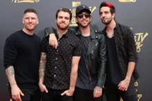 Skupina čtyř vysmátých mužů před stěnou s nápisy MTV