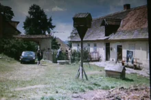 Stará chalupa a dvorek s auty na české vesnici, kde se zrovna natáčí film