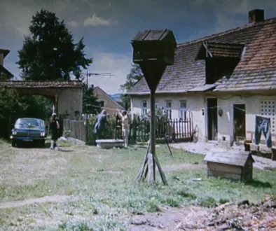 Stará chalupa a dvorek s auty na české vesnici, kde se zrovna natáčí film