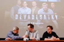 Tři muži sedí u stolu v sále, za nimi je velké plátno a na něm svítí fotografie s nápisem Devadesátky