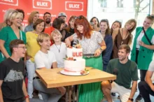 Dospělí a děti stojí u dortu a za nimi je stěna s logem oblíbeného českého seriálu