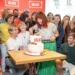 Dospělí a děti stojí u dortu a za nimi je stěna s logem oblíbeného českého seriálu