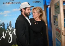 Muž a žena stojí blízko u sebe před filmovým plakátem, kterému dominuje modrá barva